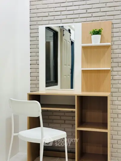 Modern study nook with wooden desk, white chair, and decorative plant against a brick wall.