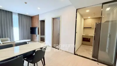 Modern open-plan living and dining area with sleek kitchen in contemporary apartment.