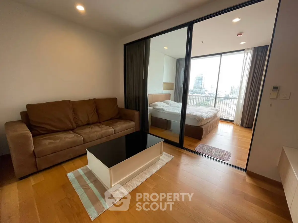 Modern apartment with cozy living room and bedroom, featuring a large window with city view.