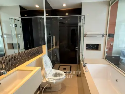 Luxurious modern bathroom with glass shower and large bathtub in upscale apartment.