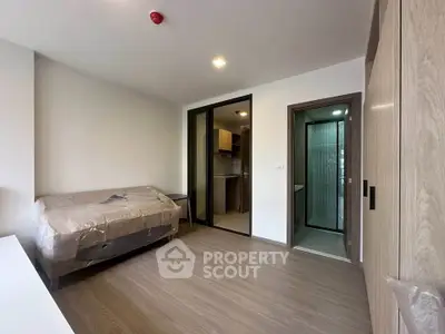 Modern studio apartment with compact kitchen and bathroom, featuring sleek wooden flooring and minimalist design.