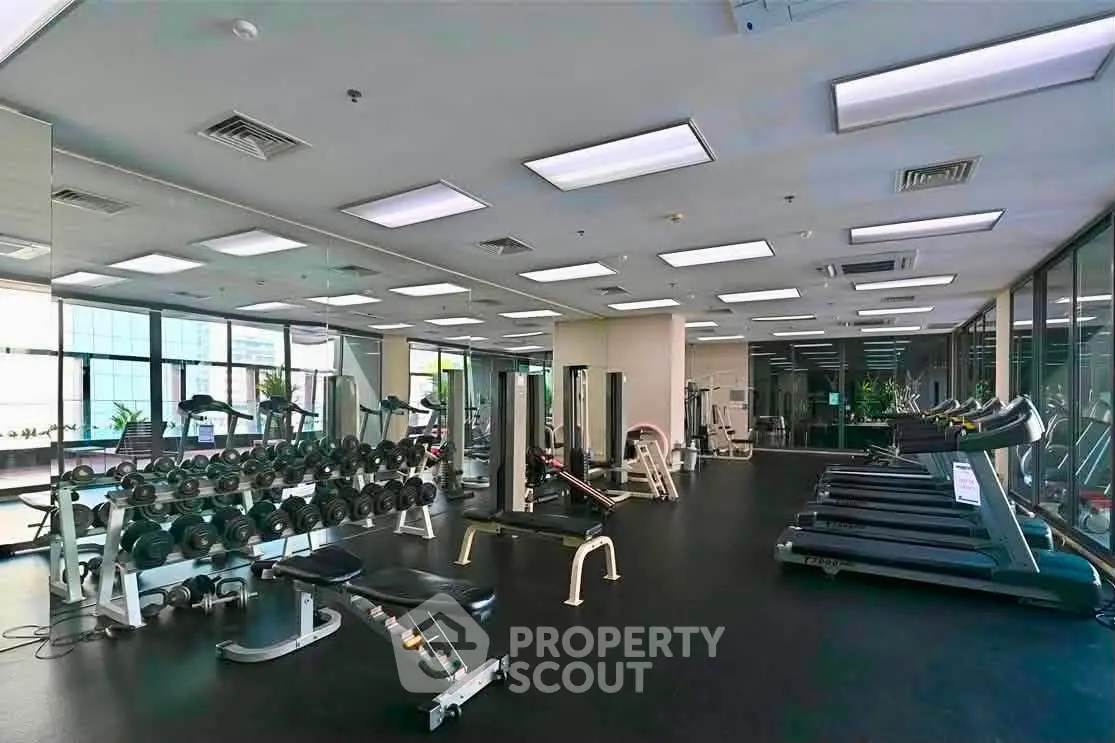 Spacious modern gym with state-of-the-art equipment and large windows for natural light.