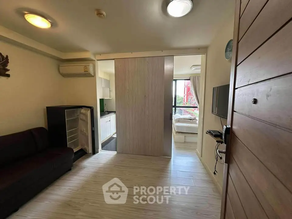 Compact apartment with open layout, featuring a cozy living area and bedroom separated by sliding doors.