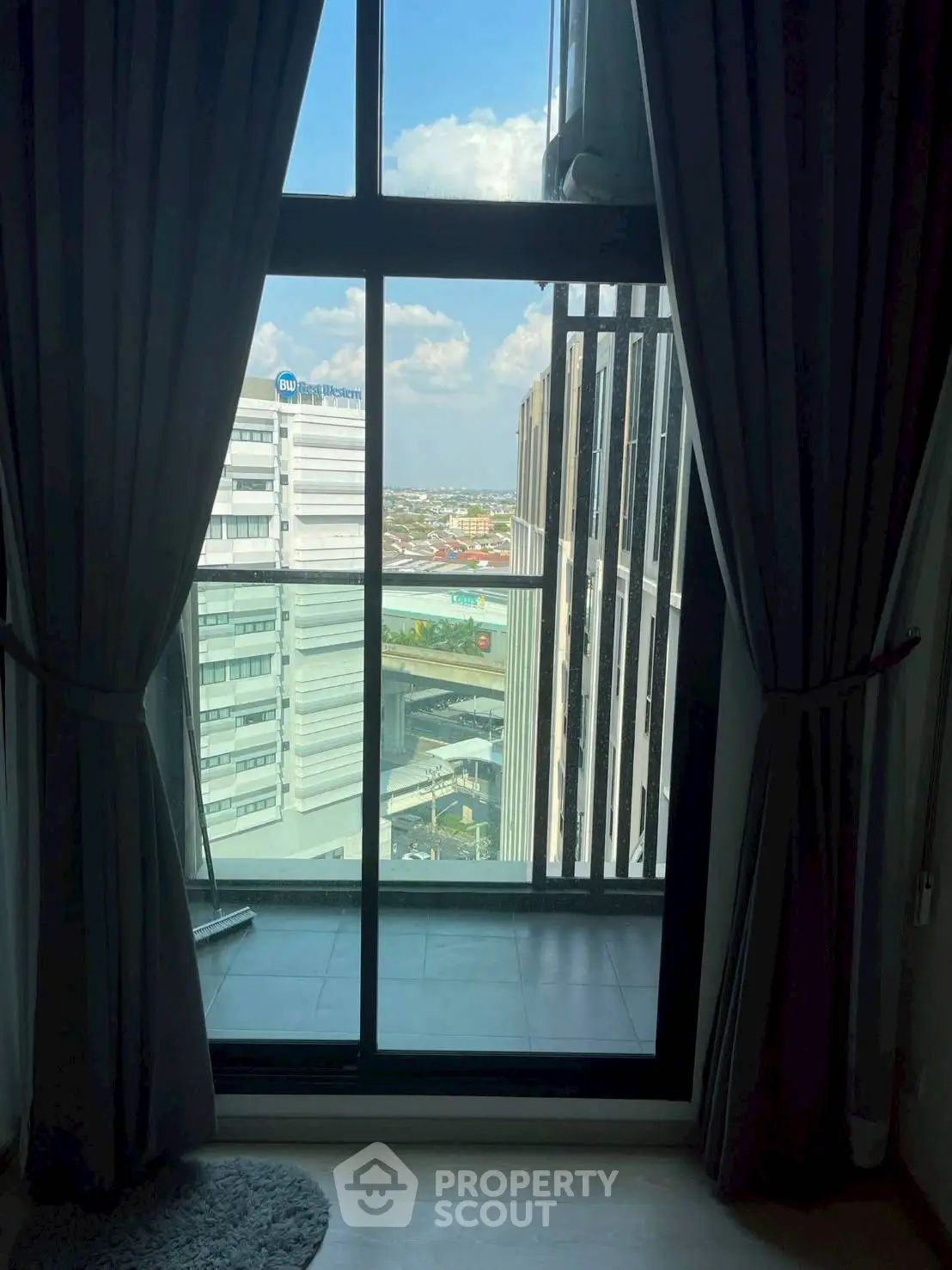 Stunning high-rise apartment view with floor-to-ceiling windows and cityscape backdrop.