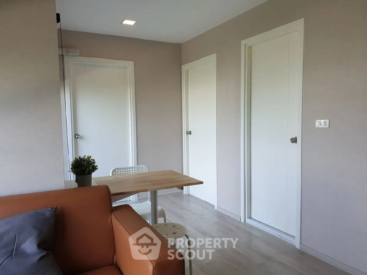 Modern living room with minimalist decor and neutral tones, featuring a cozy sofa and dining table.