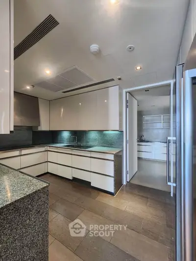 Modern kitchen with sleek cabinetry and granite countertops in luxury apartment