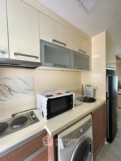 Modern kitchen with washing machine and microwave in compact layout
