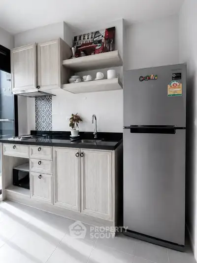 Modern kitchen with sleek cabinets and stainless steel fridge in stylish apartment.