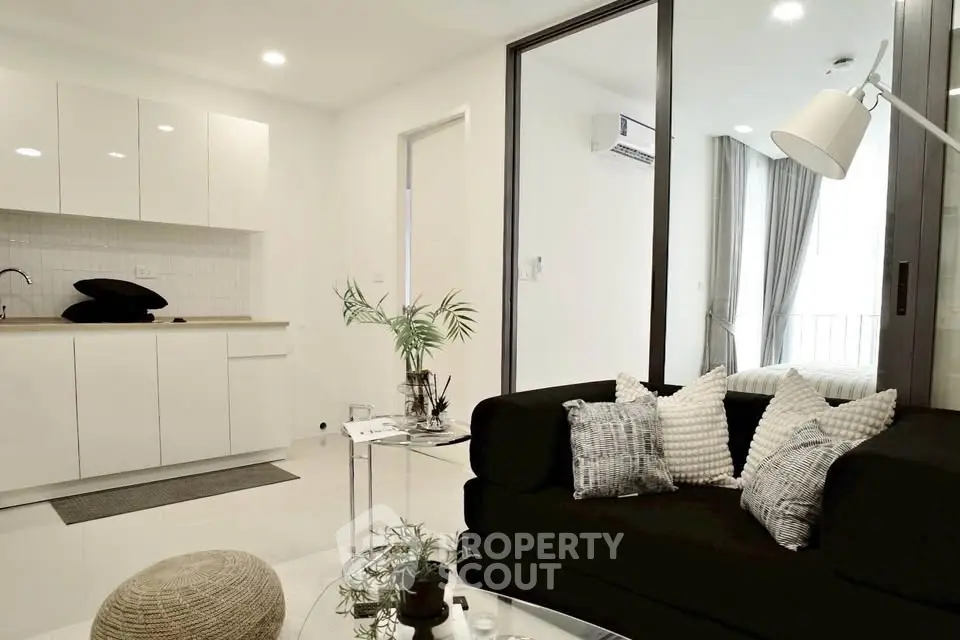Modern living room with sleek black sofa and minimalist kitchen design