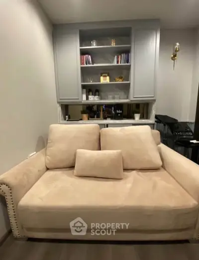 Cozy living room with plush beige sofa and built-in shelving, perfect for relaxation and reading.