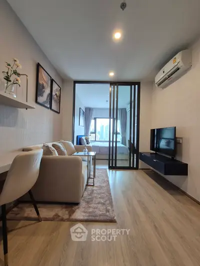 Modern living room with sliding glass doors leading to a cozy bedroom, featuring stylish decor and natural light.