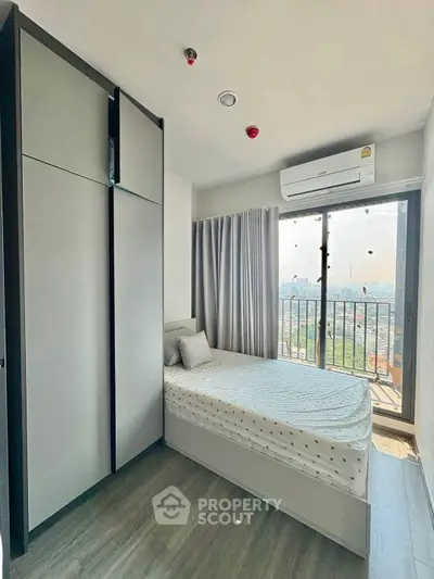 Modern bedroom with city view, featuring sleek wardrobe and air conditioning.