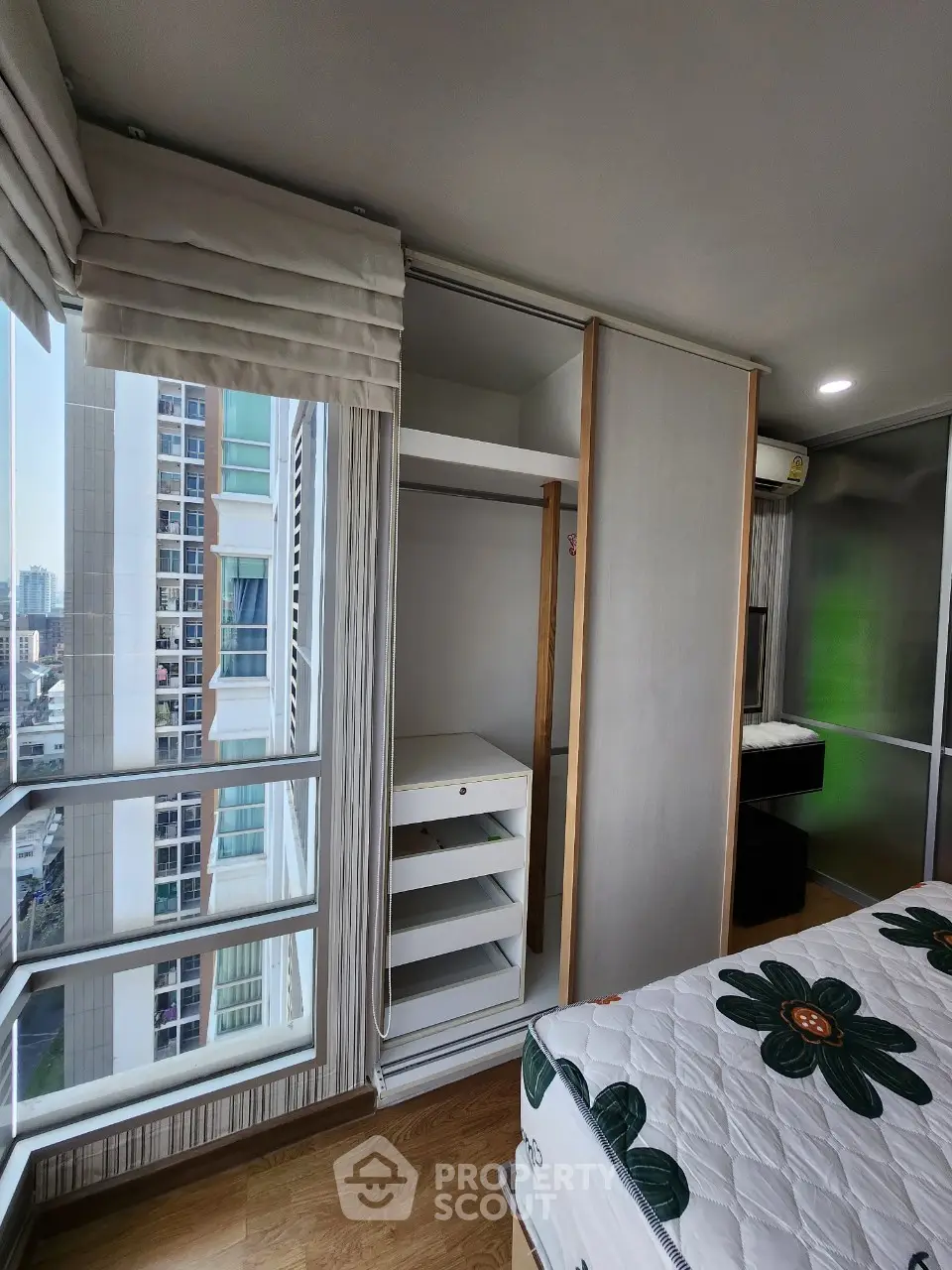 Modern bedroom with large windows and built-in closet in high-rise apartment.