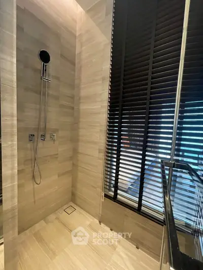 Modern bathroom with elegant wall tiles and sleek shower fixtures, complemented by stylish blinds and natural light.