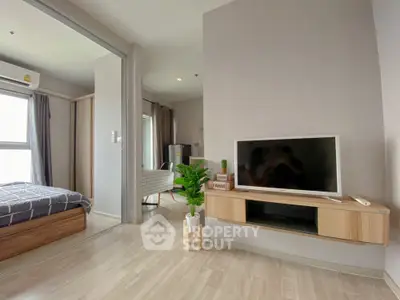 Modern living room with TV and view into cozy bedroom