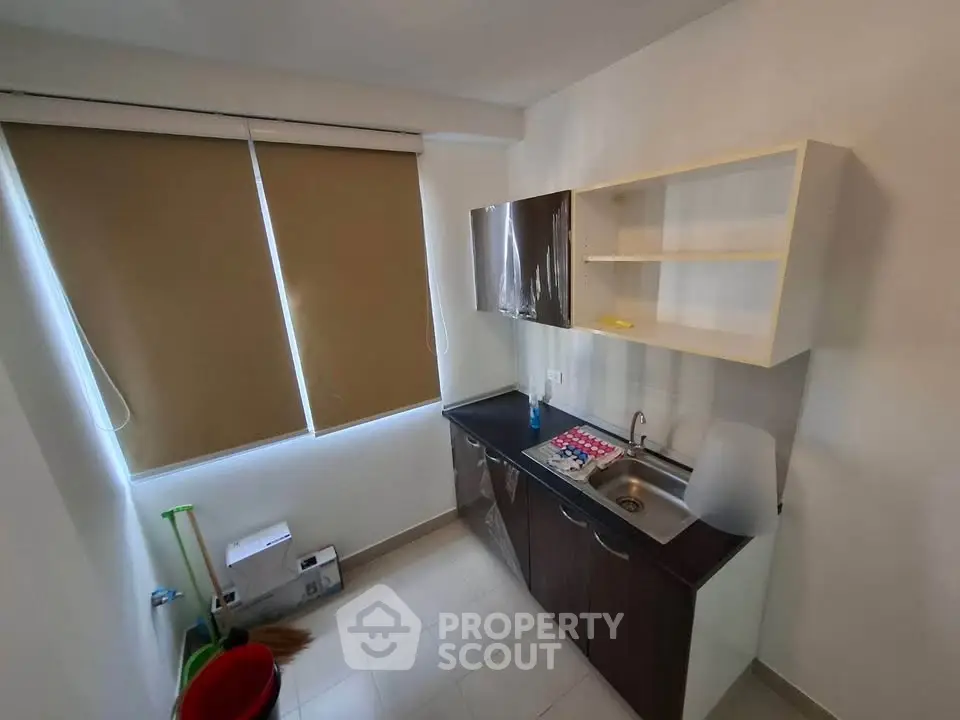 Compact kitchen with modern cabinets and sink, featuring a closed layout and natural light from window.