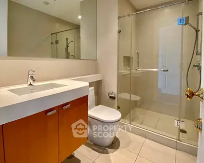 Modern bathroom with glass shower and sleek vanity in contemporary home.