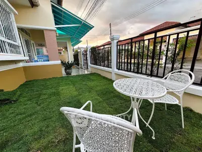 Charming garden area with elegant white patio furniture and lush green lawn, perfect for relaxation.