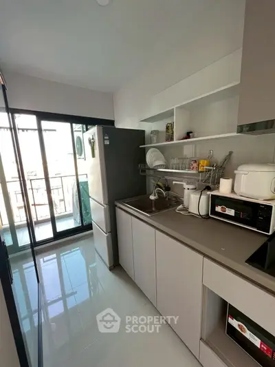 Modern kitchen with sleek cabinets and appliances, featuring a balcony view.