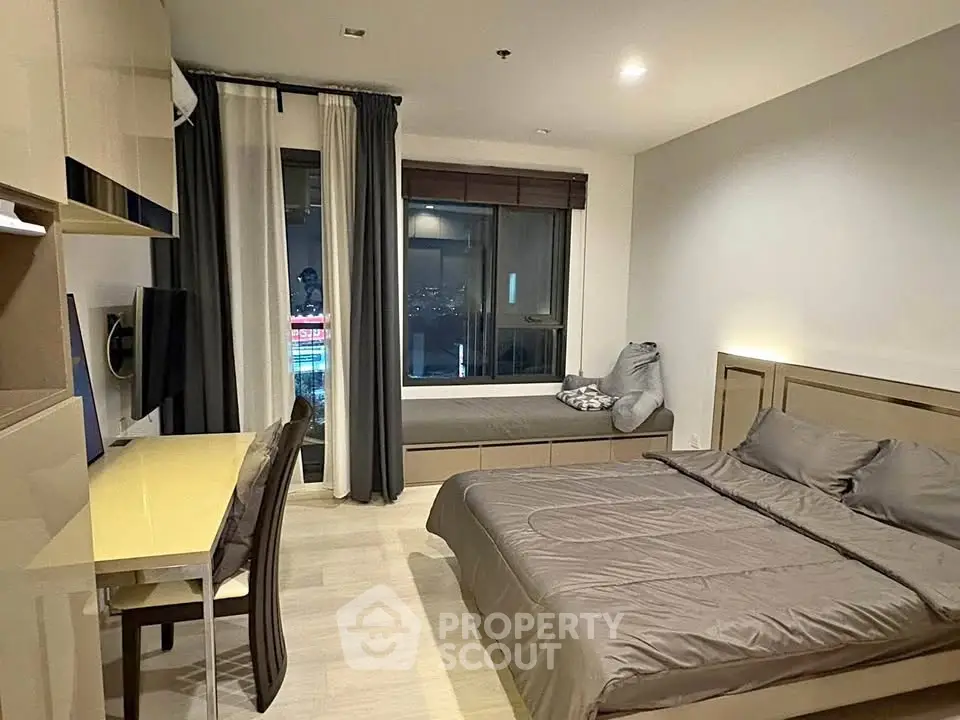 Modern bedroom with sleek furniture and city view window, perfect for urban living.