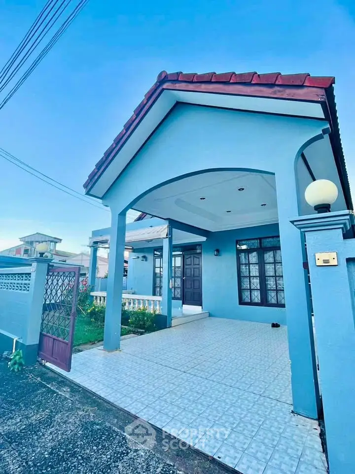 Charming blue single-story house with tiled entrance and elegant archway, perfect for cozy living.