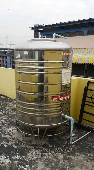Stainless steel water tank on rooftop with pipes, ideal for efficient water storage in urban buildings.