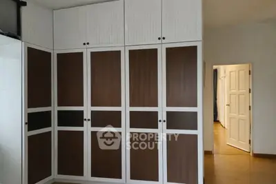 Spacious bedroom with elegant built-in wardrobes and open door to hallway.