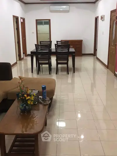 Spacious living room with modern furniture and tiled flooring, perfect for family gatherings.