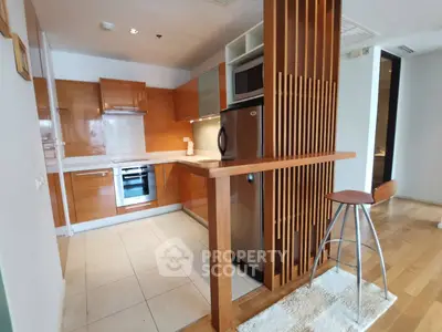 Modern kitchen with sleek wooden cabinetry and stainless steel appliances in open layout.