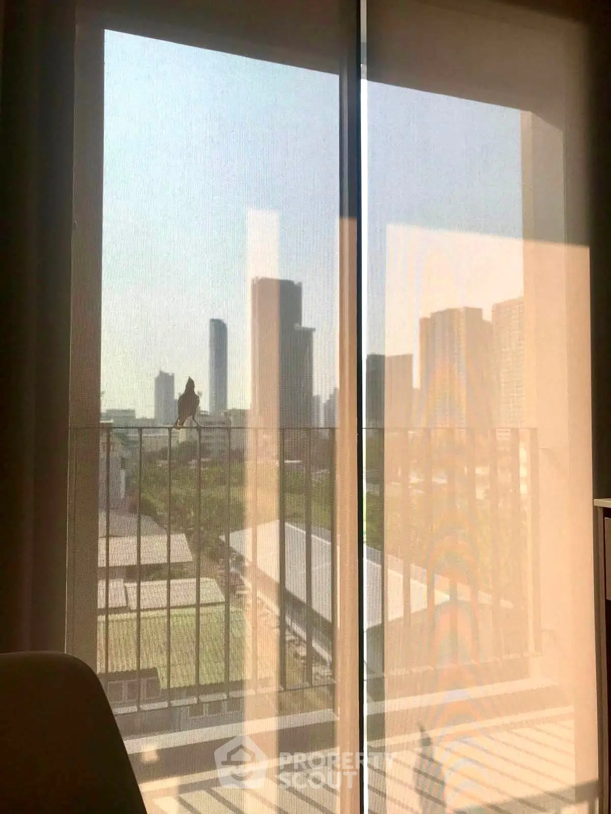 Stunning city view from modern apartment balcony with floor-to-ceiling windows.