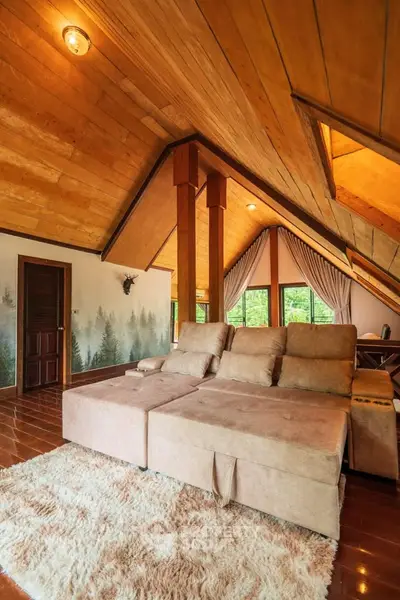 Charming attic living room with cozy sofa and wooden ceiling, perfect for relaxation.