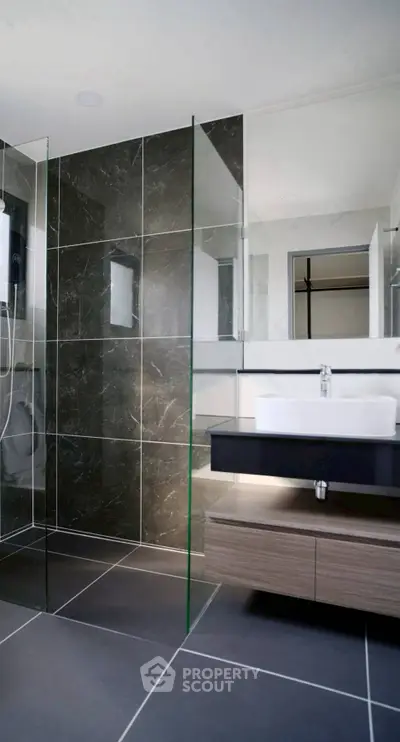 Modern bathroom with sleek glass shower and stylish vanity in luxury apartment.