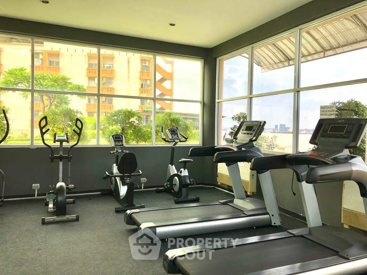Modern gym with cardio equipment and city view in luxury apartment complex.
