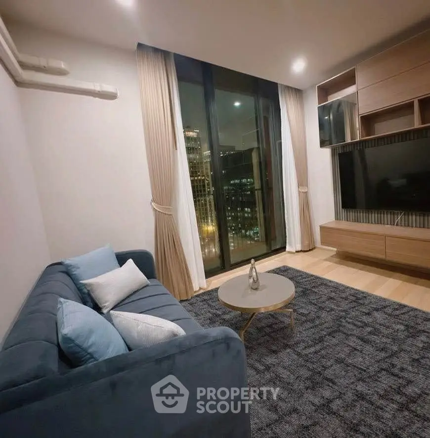 Modern living room with large window and city view, featuring stylish furniture and elegant decor.