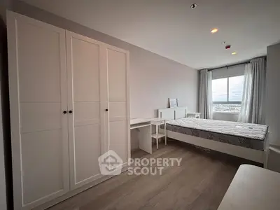 Spacious bedroom with large window and modern furnishings, offering a serene and comfortable living space.