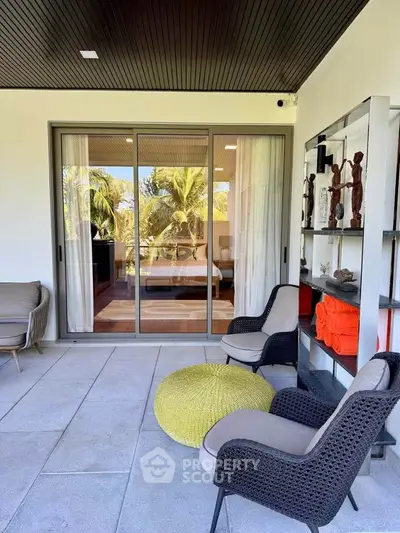 Luxurious balcony with stylish seating and tropical view, perfect for relaxation.