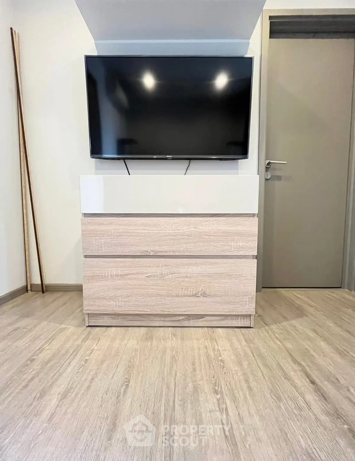 Modern living room with sleek TV setup and stylish wooden flooring.