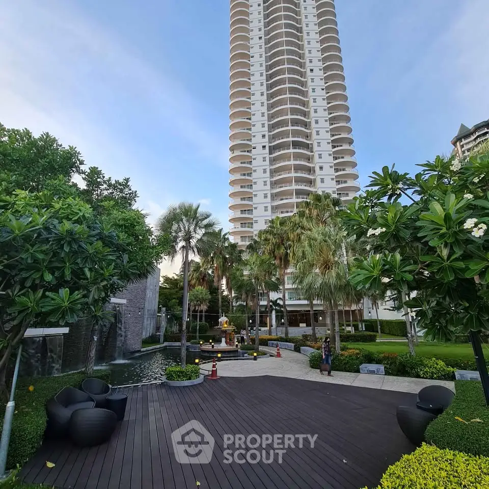 Luxurious high-rise building with lush garden and modern outdoor seating area.