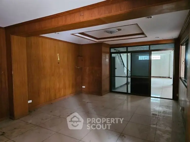 Spacious living room with wooden paneling and large windows for natural light.