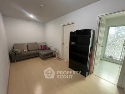Cozy living room with modern sofa and bookshelf, adjacent to a bright bathroom.