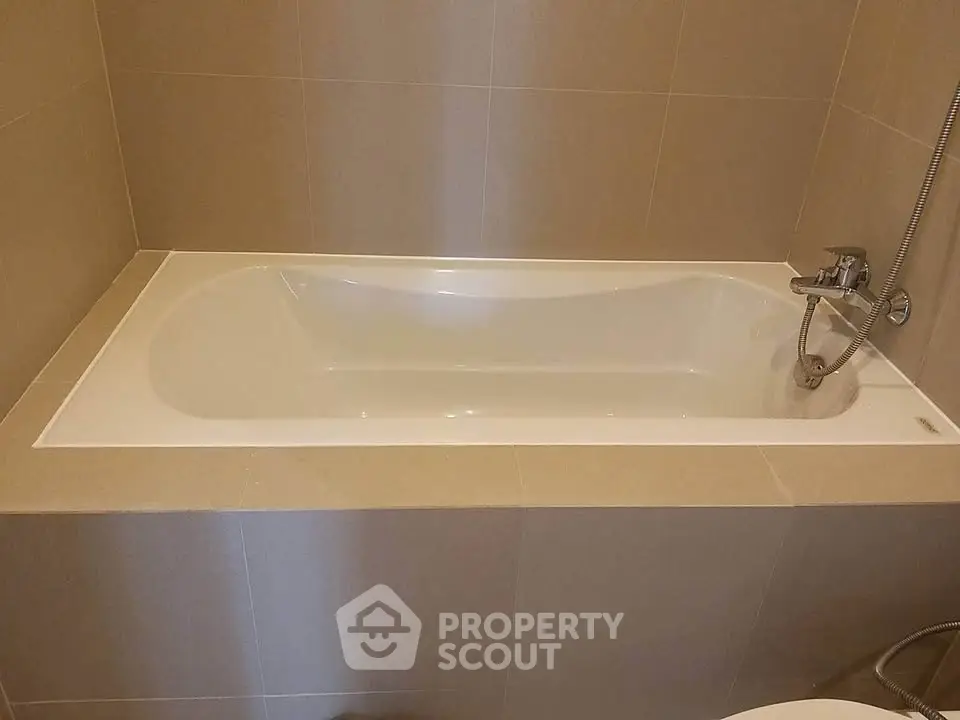Modern bathroom with sleek bathtub and neutral tile design.