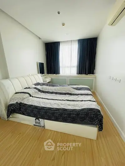 Modern bedroom with stylish decor and natural light, featuring a comfortable bed and sleek wooden flooring.