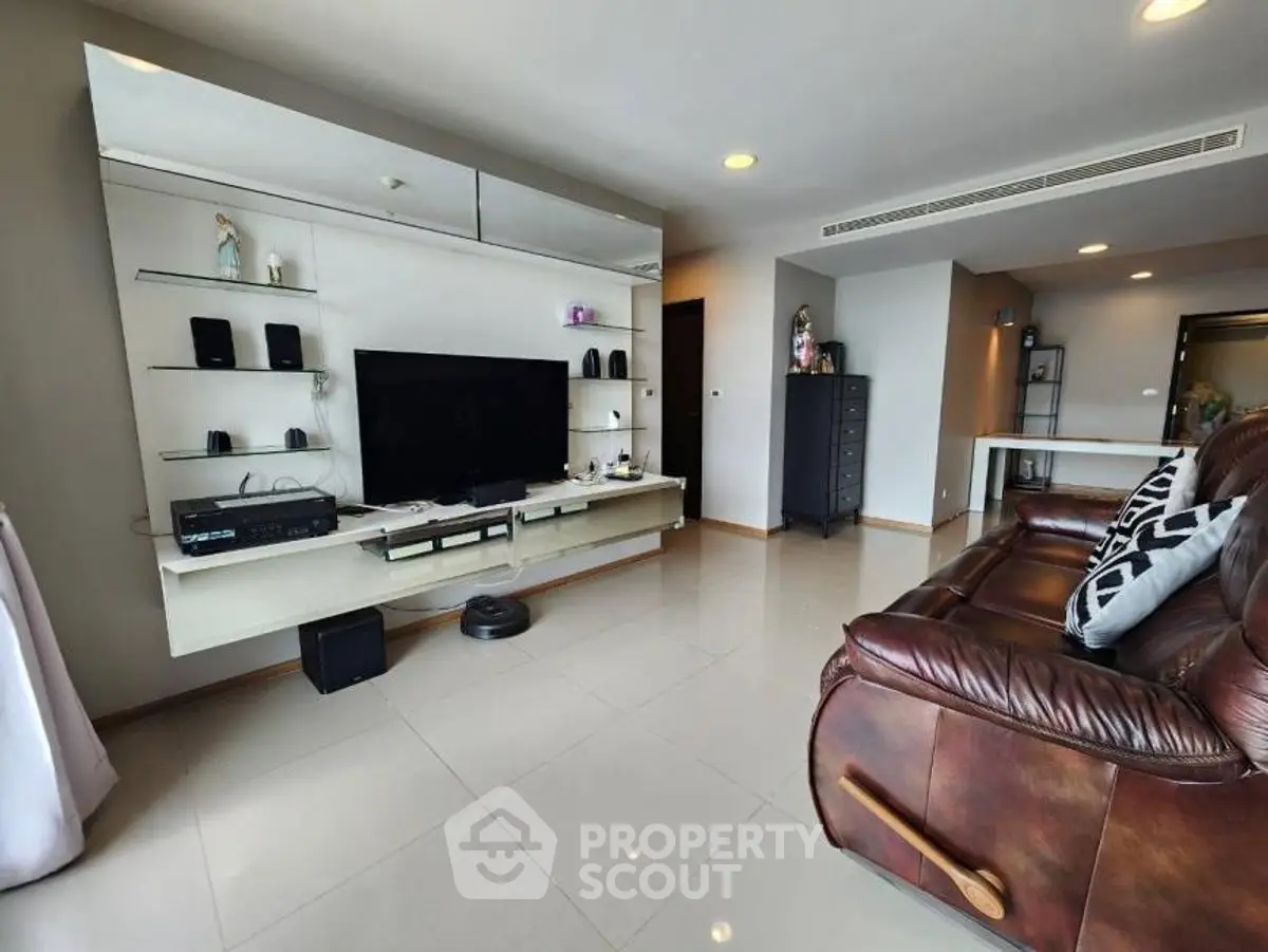 Spacious living room with modern entertainment center and leather sofa in a stylish apartment.