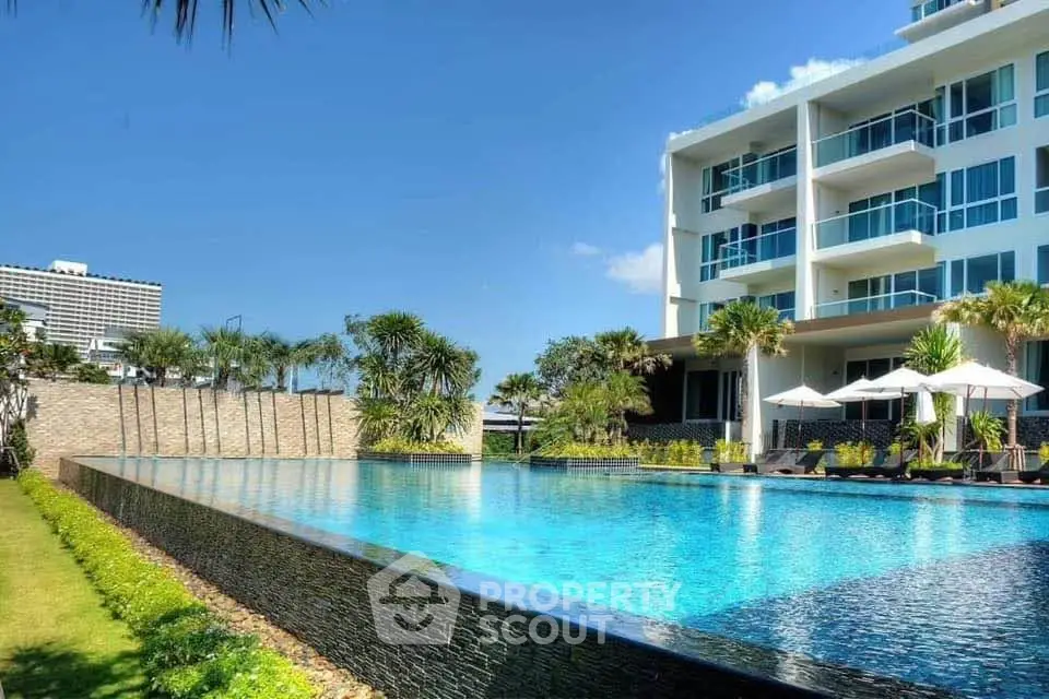 Luxurious apartment complex with stunning pool and modern architecture under clear blue sky.