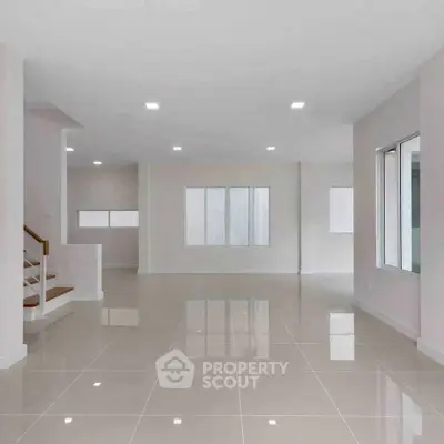 Spacious open-plan living area with glossy tiled floors and ample natural light.