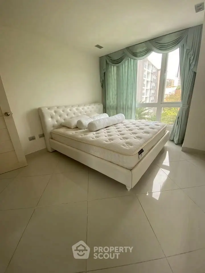 Spacious bedroom with elegant decor and large windows offering natural light.