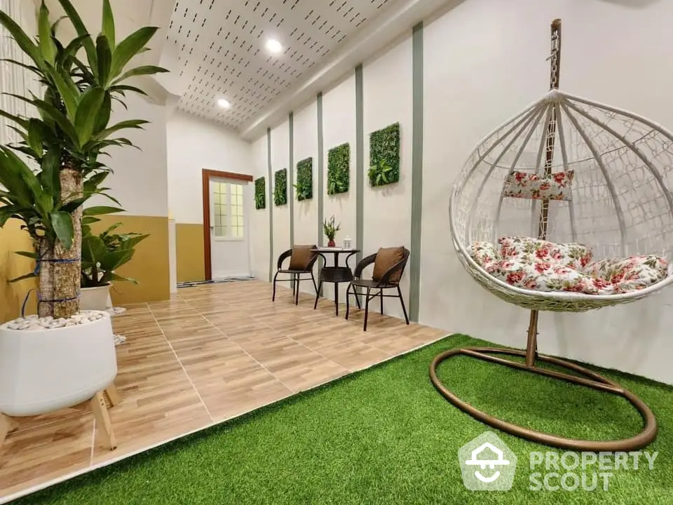 Spacious and vibrant living area with a unique hanging egg chair, artificial grass flooring, and decorative green wall panels, perfect for modern living.