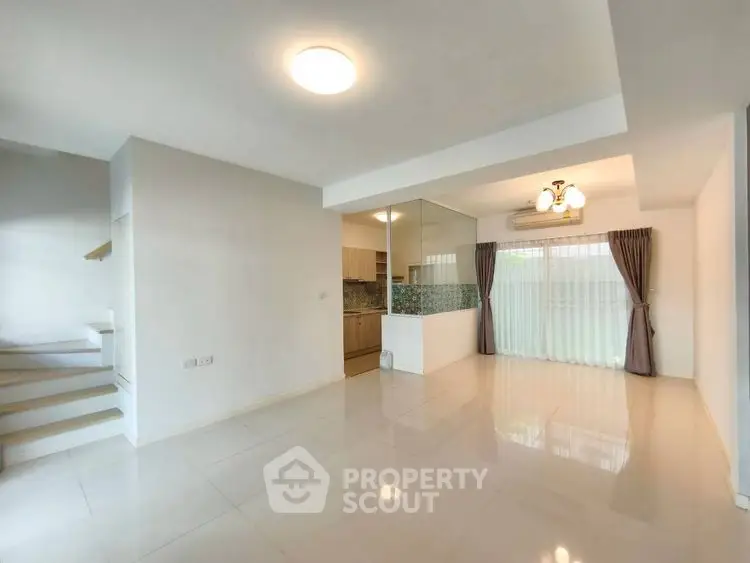 Spacious open-plan living area with modern kitchen and elegant lighting.