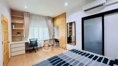 Modern bedroom with study area, featuring built-in wardrobe and large window for natural light.