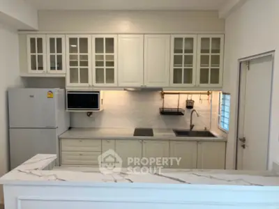 Modern kitchen with white cabinetry, marble countertop, and built-in appliances.